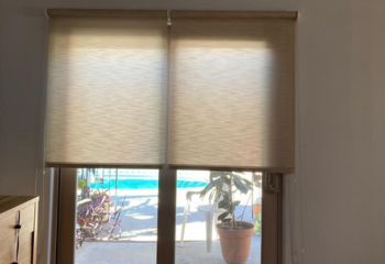 Pull down sheer window shades partially raised on a bedroom patio door in Concord, allowing filtered light and a view outside.