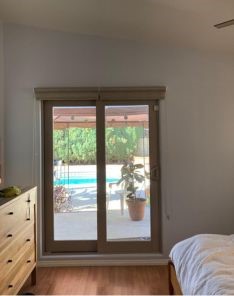 Clear view of a Concord bedroom patio door with custom roller shades fully open, showcasing the seamless indoor-outdoor connection and stylish window treatment.
